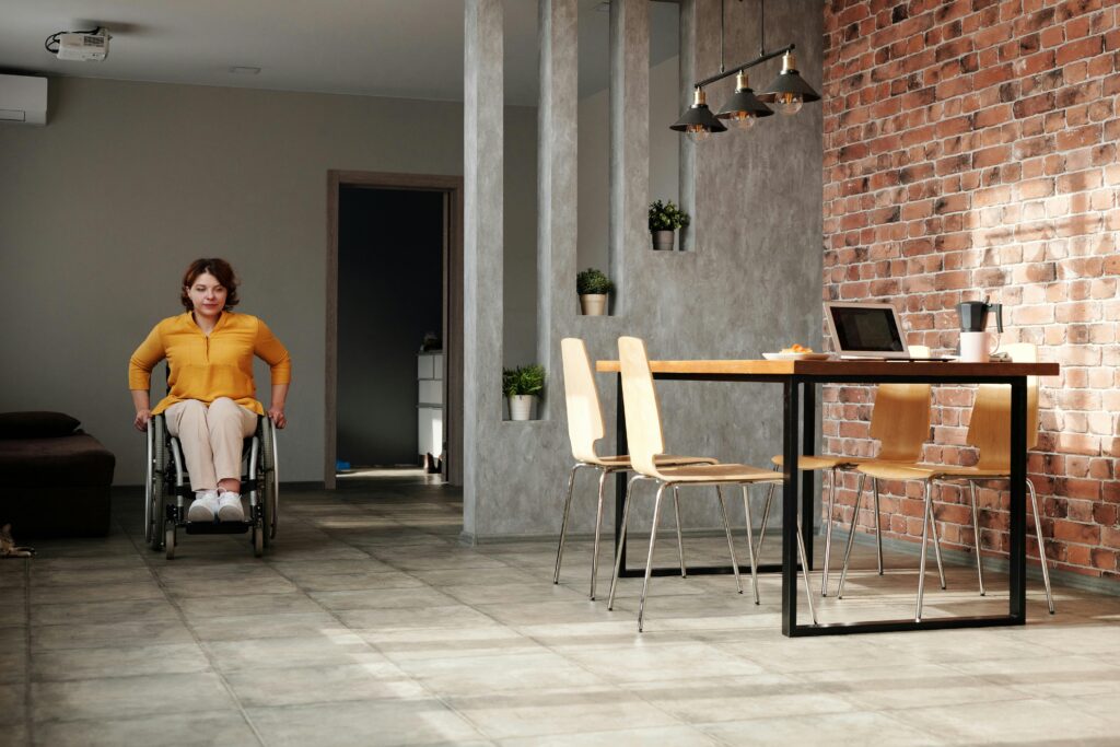 A woman in a wheelchair navigating a modern home office space with brick walls.