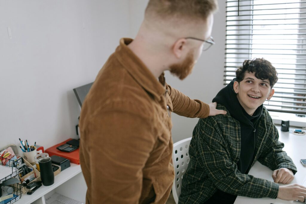 A friendly interaction between two male colleagues in a modern office setting.